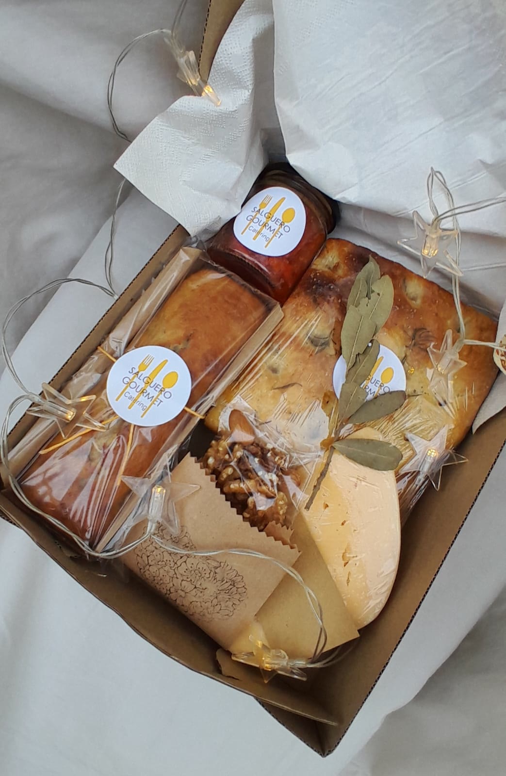 Box gourmet con budín, focaccia, queso, mermelada y nueces, con luces y sticker de Salguero Gourmet