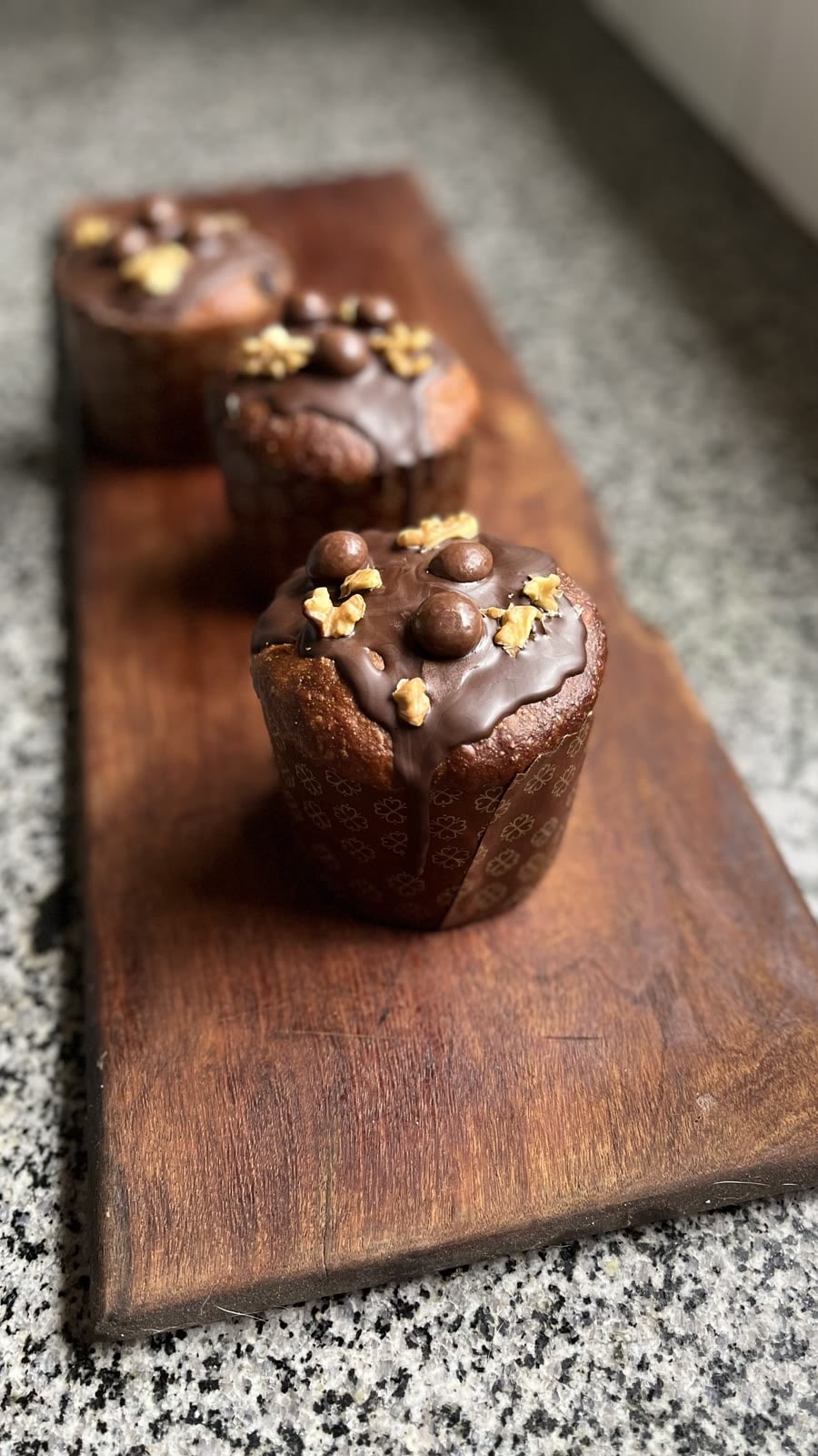 Budines de chocolate con glaseado y nuez sobre tabla de madera